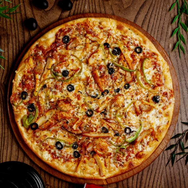 Pizza Fiore's chicken pizza with black olives and green bell peppers on a wooden board.